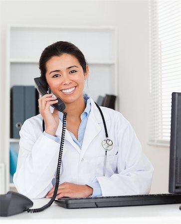 simsearch:400-05350424,k - Good looking woman doctor on the phone while sitting in her office Foto de stock - Super Valor sin royalties y Suscripción, Código: 400-04415053