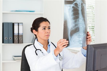 simsearch:400-05350424,k - Gorgeous female doctor looking at a x-ray in her office Foto de stock - Super Valor sin royalties y Suscripción, Código: 400-04415069