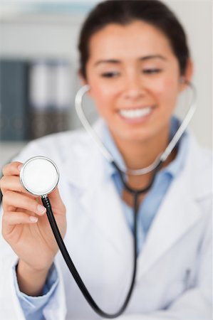 simsearch:400-05350424,k - Gorgeous female doctor using a stethoscope while looking at the camera in her office Foto de stock - Super Valor sin royalties y Suscripción, Código: 400-04415093