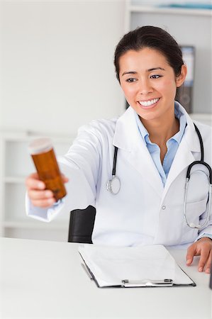 simsearch:400-05350424,k - Lovely smiling doctor holding a box of pills while sitting in her office Foto de stock - Super Valor sin royalties y Suscripción, Código: 400-04415863