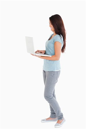 full body student holding laptop - Gorgeous woman relaxing with her laptop while standing against a white background Stock Photo - Budget Royalty-Free & Subscription, Code: 400-04416014