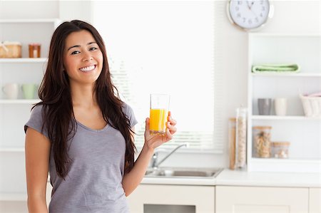 simsearch:400-04416091,k - Attractive woman holding a glass of orange juice while standing in the kitchen Fotografie stock - Microstock e Abbonamento, Codice: 400-04416104
