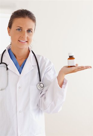simsearch:400-05728493,k - Good looking brunette doctor with stethoscope looking at some pills in the surgery Photographie de stock - Aubaine LD & Abonnement, Code: 400-04417387