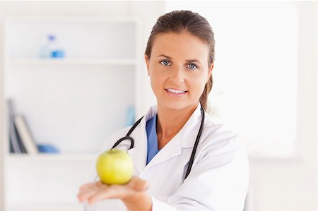 simsearch:400-05728493,k - Doctor with stethoscope holding an apple looking into the camera in the surgery Photographie de stock - Aubaine LD & Abonnement, Code: 400-04417389