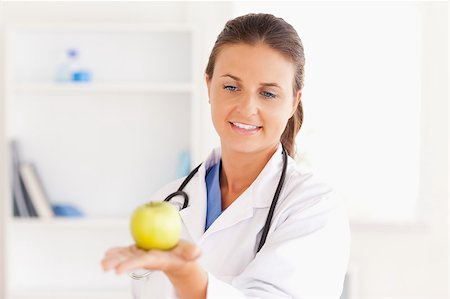 simsearch:400-05728493,k - Smiling doctor with stethoscope holding an apple in the surgery Photographie de stock - Aubaine LD & Abonnement, Code: 400-04417390
