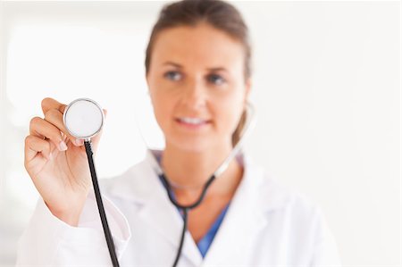 simsearch:400-05892402,k - gorgeous brunette doctor showing stethoscope to the camera in the surgery Stock Photo - Budget Royalty-Free & Subscription, Code: 400-04417392