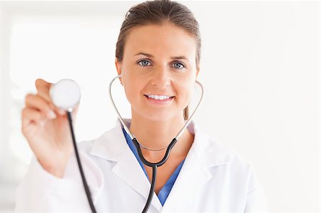 simsearch:400-05728490,k - gorgeous brunette doctor showing stethoscope looking into the camera in her surgery Photographie de stock - Aubaine LD & Abonnement, Code: 400-04417393