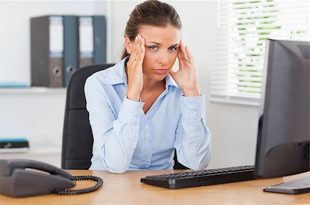 phone with pain - A stressed businesswoman is sitting at workplace in an office while looking into the camera Stock Photo - Budget Royalty-Free & Subscription, Code: 400-04417409