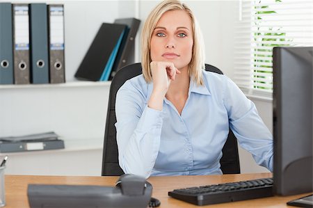 Serious woman with chin on hand behind a desk in an office Stock Photo - Budget Royalty-Free & Subscription, Code: 400-04417546