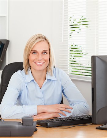 Smiling blonde woman sitting behind a desk in an office Stock Photo - Budget Royalty-Free & Subscription, Code: 400-04417540