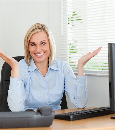 Smiling woman sitting behind desk not having a clue what to do next inan office Stock Photo - Budget Royalty-Free & Subscription, Code: 400-04417556