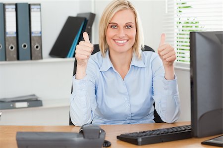 Young woman sitting behind desk with thumbs up in an office Stock Photo - Budget Royalty-Free & Subscription, Code: 400-04417551