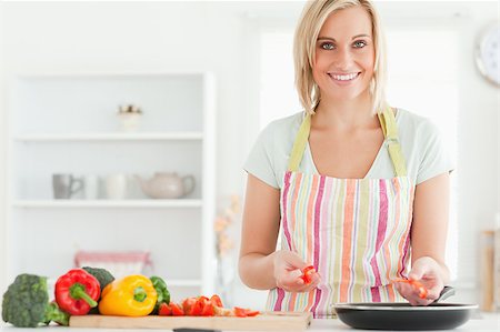 simsearch:400-04139196,k - Close up of a young woman frying peppers looking into the camera in the kitchen Foto de stock - Royalty-Free Super Valor e Assinatura, Número: 400-04417716