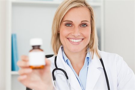 simsearch:400-04417775,k - Gorgeous blonde doctor holding medicine to camera in her office Foto de stock - Super Valor sin royalties y Suscripción, Código: 400-04417758