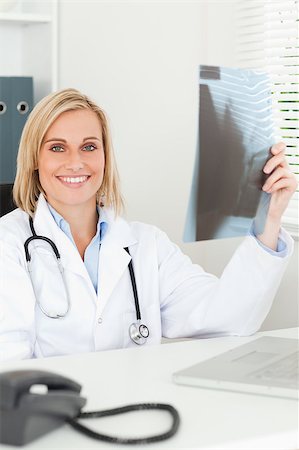 simsearch:400-04417775,k - Charming doctor holding x-ray smiles into camera in her office Foto de stock - Super Valor sin royalties y Suscripción, Código: 400-04417769