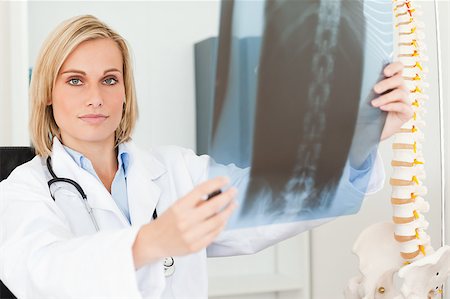 simsearch:400-04417775,k - Serious doctor looking at x-ray looks into camera in her office Foto de stock - Super Valor sin royalties y Suscripción, Código: 400-04417770