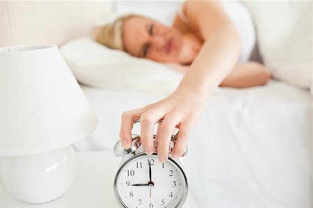 simsearch:400-04287303,k - Upset woman switching off her alarm clock in her bedroom Stockbilder - Microstock & Abonnement, Bildnummer: 400-04418603