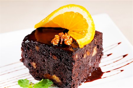 fresh baked delicious chocolate and walnuts cake with slice of orance on top and mint leaf Photographie de stock - Aubaine LD & Abonnement, Code: 400-04418957