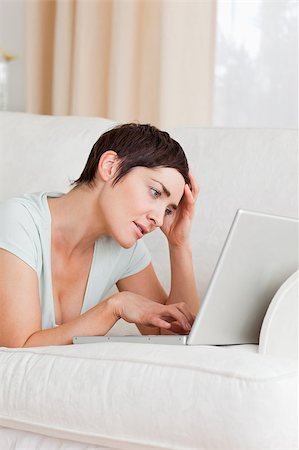 simsearch:400-05209351,k - Tired young woman using a laptop in her living room Stock Photo - Budget Royalty-Free & Subscription, Code: 400-04410650