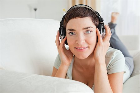 Short-haired brunette listening to music while looking at the camera Stock Photo - Budget Royalty-Free & Subscription, Code: 400-04410732
