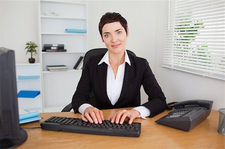 simsearch:400-04894274,k - Smiling secretary typing on her keybord in her office Stock Photo - Budget Royalty-Free & Subscription, Code: 400-04410826