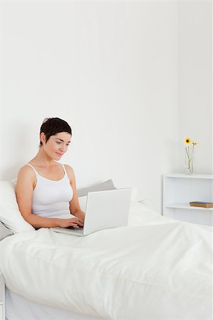simsearch:400-04206266,k - Good looking brunette using a laptop in her bedroom Stockbilder - Microstock & Abonnement, Bildnummer: 400-04410869
