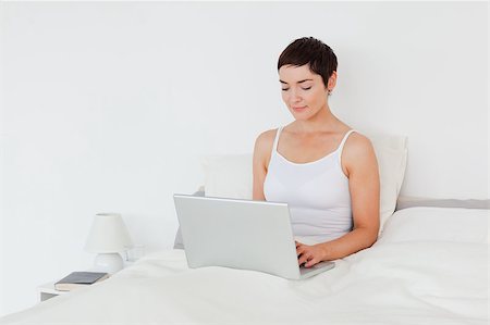 simsearch:400-04206266,k - Charming brunette using a laptop in her bedroom Stockbilder - Microstock & Abonnement, Bildnummer: 400-04410914