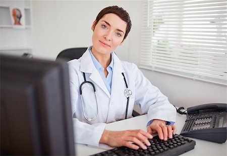 doctor business computer - Cute female doctor typing with her computer in her office Stock Photo - Budget Royalty-Free & Subscription, Code: 400-04410989