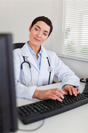 doctor business computer - Portrait of a charming female doctor typing with her computer in her office Stock Photo - Budget Royalty-Free & Subscription, Code: 400-04410991