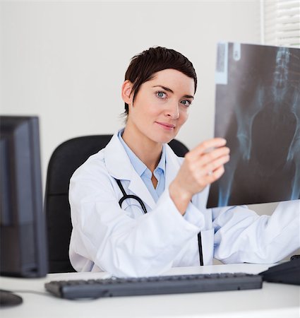 Focused female doctor holding a set of X-ray while lookinigat the camera Stock Photo - Budget Royalty-Free & Subscription, Code: 400-04411003