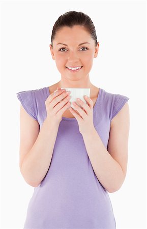 Good looking woman enjoying a cup of coffee while standing against a white background Stock Photo - Budget Royalty-Free & Subscription, Code: 400-04411069