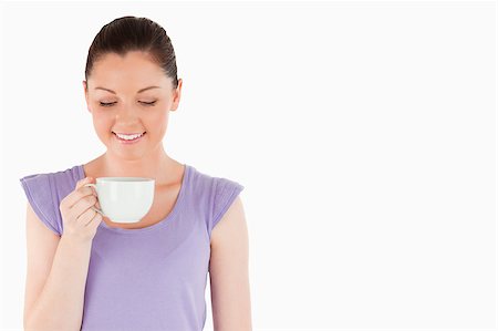 Lovely woman enjoying a cup of coffee while standing against a white background Stock Photo - Budget Royalty-Free & Subscription, Code: 400-04411074
