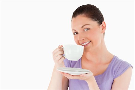 Cute woman enjoying a cup of coffee while standing against a white background Stock Photo - Budget Royalty-Free & Subscription, Code: 400-04411075