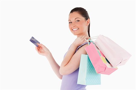 simsearch:400-05156727,k - Attractive woman with a credit card holding shopping bags while standing against a white background Foto de stock - Super Valor sin royalties y Suscripción, Código: 400-04411094