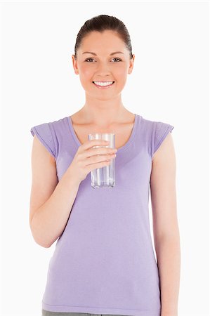 Charming woman holding a glass of water while standing against a white background Stock Photo - Budget Royalty-Free & Subscription, Code: 400-04411152