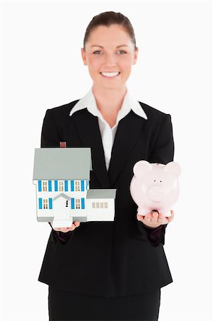 simsearch:400-05156727,k - Charming woman in suit holding a piggy bank and a miniature house while standing against a white background Foto de stock - Super Valor sin royalties y Suscripción, Código: 400-04411322