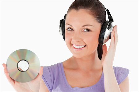 simsearch:400-06690896,k - Attractive woman with headphones holding a CD while standing against a white background Stock Photo - Budget Royalty-Free & Subscription, Code: 400-04411461