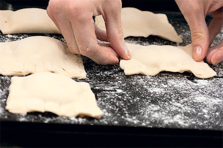 simsearch:649-06845216,k - Pair of hands laying out raw pastries on a baking tray Photographie de stock - Aubaine LD & Abonnement, Code: 400-04411898