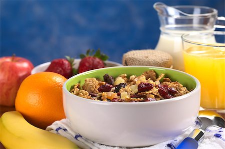 simsearch:400-04891088,k - Delicious healthy breakfast with a bowl full of wholewheat flakes mixed with dried fruits (cranberries, bananas, raisins and some others) and nuts with fresh fruits, yogurt, milk and orange juice around (Selective Focus, Focus one third into the bowl) Stock Photo - Budget Royalty-Free & Subscription, Code: 400-04411946