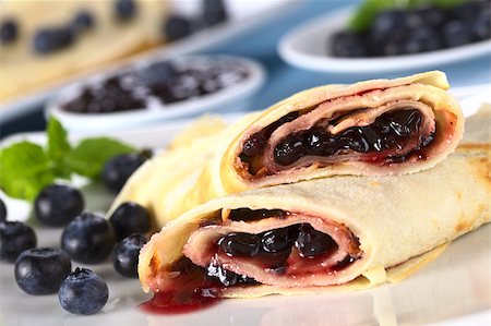 Pancakes filled with blueberry jam with fresh blueberries on the plate and jam in the back (Selective Focus, Focus on the front of the upper pancake roll) Stock Photo - Budget Royalty-Free & Subscription, Code: 400-04411954