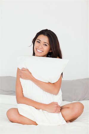 smiling woman with pillow sitting on her bed looking into camera in bedroom Stock Photo - Budget Royalty-Free & Subscription, Code: 400-04413714