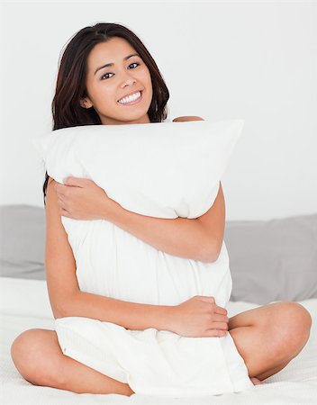 cute woman with pillow sitting on her bed smiling into camera in bedroom Stock Photo - Budget Royalty-Free & Subscription, Code: 400-04413713