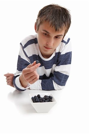 A boy looking intensely at a blueberry held between two fingers. Photographie de stock - Aubaine LD & Abonnement, Code: 400-04424586