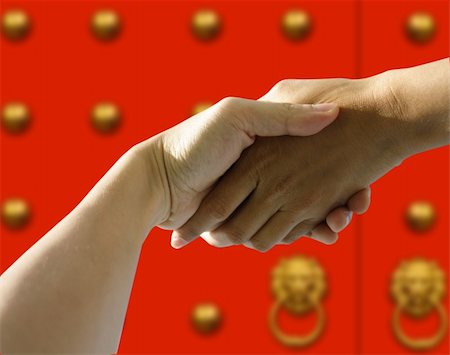 A pair of hands holding or shaking each other against a chinese red door. Concept: Business in china Stock Photo - Budget Royalty-Free & Subscription, Code: 400-04429699