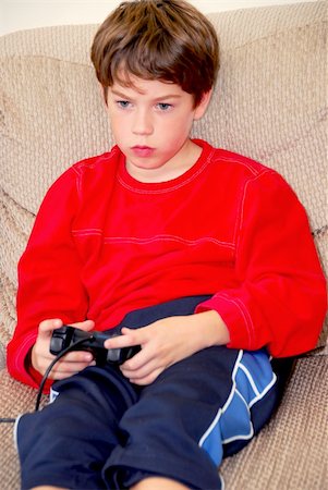 simsearch:400-05059261,k - Young boy playing a video game sitting on a couch Stock Photo - Budget Royalty-Free & Subscription, Code: 400-04429926