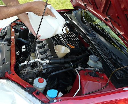 eichmaß - Male adding oil with a funnel from the left side of a red car after a do-it-yourself oil change. Dipstick is nearby. Stockbilder - Microstock & Abonnement, Bildnummer: 400-04422952