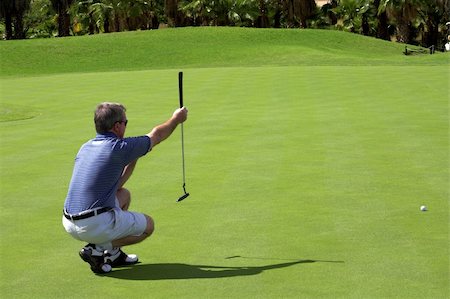 simsearch:400-04942072,k - Golfer sitting down on the green, lining up the putter. Foto de stock - Royalty-Free Super Valor e Assinatura, Número: 400-04434728