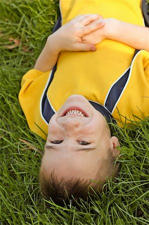 smiley face boy - A young boy laying in the grass upside down Stock Photo - Budget Royalty-Free & Subscription, Code: 400-04436281