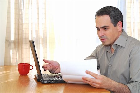 Man sitting at his desk with a laptop looking at bills Stock Photo - Budget Royalty-Free & Subscription, Code: 400-04437960