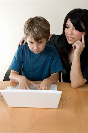 Child using a computer with adult supervision. Foto de stock - Super Valor sin royalties y Suscripción, Código: 400-04432194
